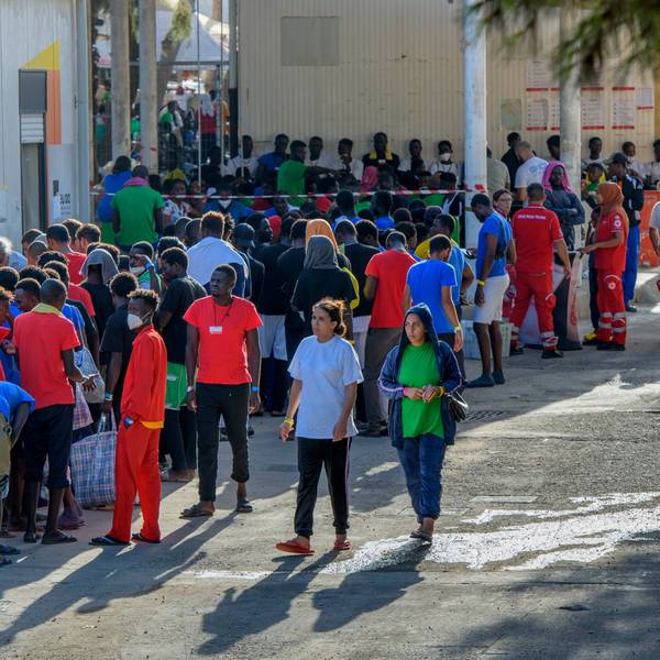 Migranten stehen vor Gebäuden auf der Insel Lampedusa.