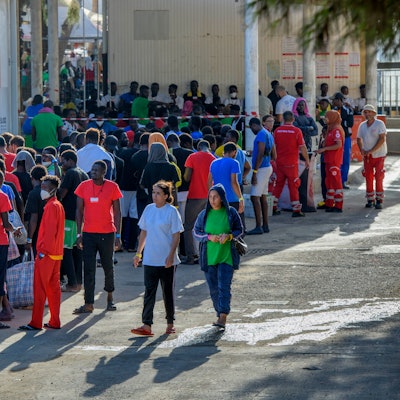 Migranten stehen vor Gebäuden auf der Insel Lampedusa.