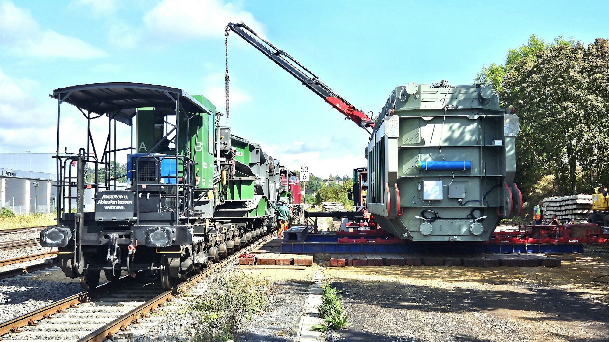 Ein Trafo (r.) für die Umspannanlage Dahlem ist am Bahnhof Kall angekommen und mit einem Kran vom Waggon abgeladen worden.