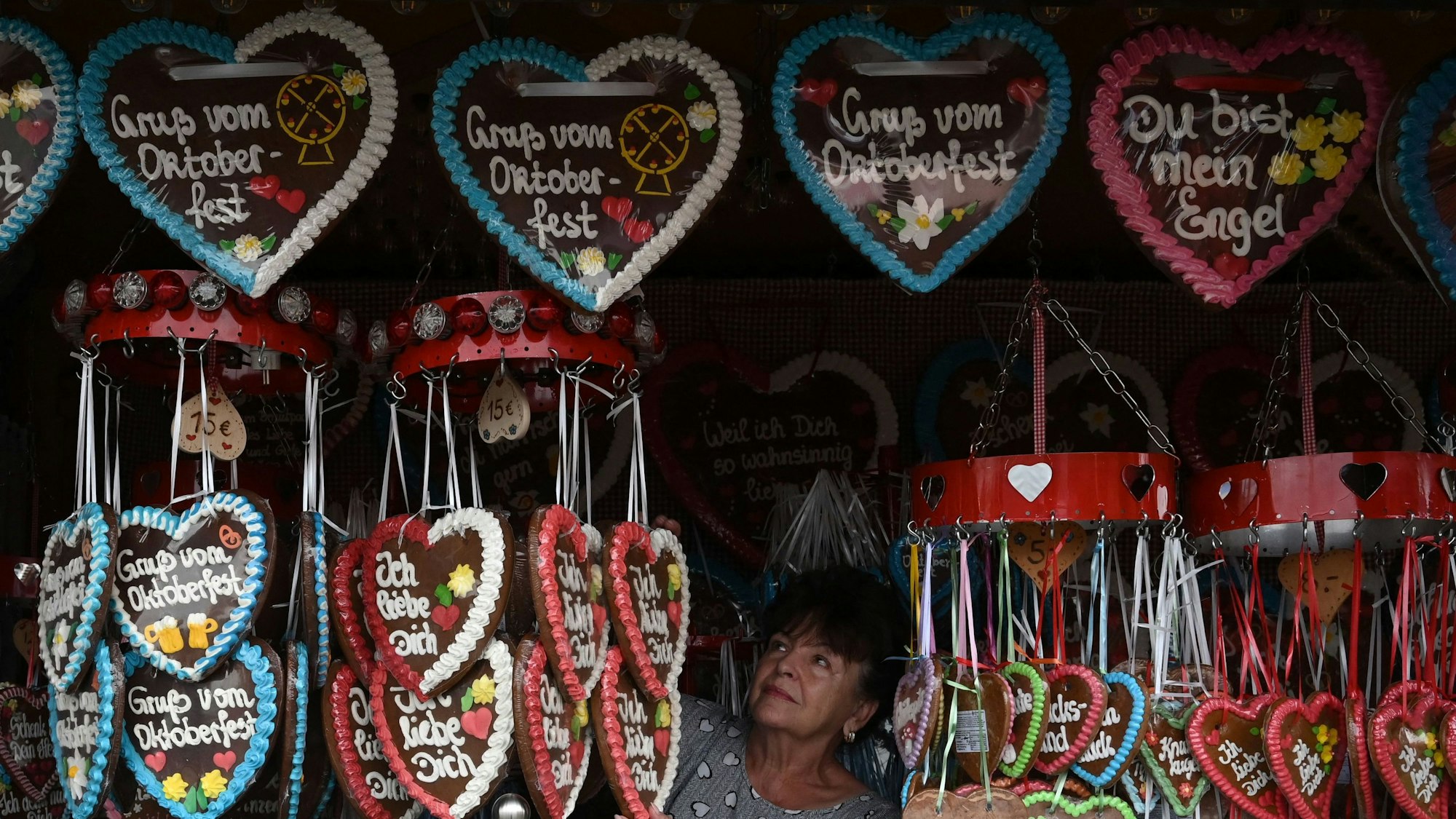 Eine Verkäuferin bereitet ihren Stand mit Lebkuchenherzen auf dem Oktoberfest vor.