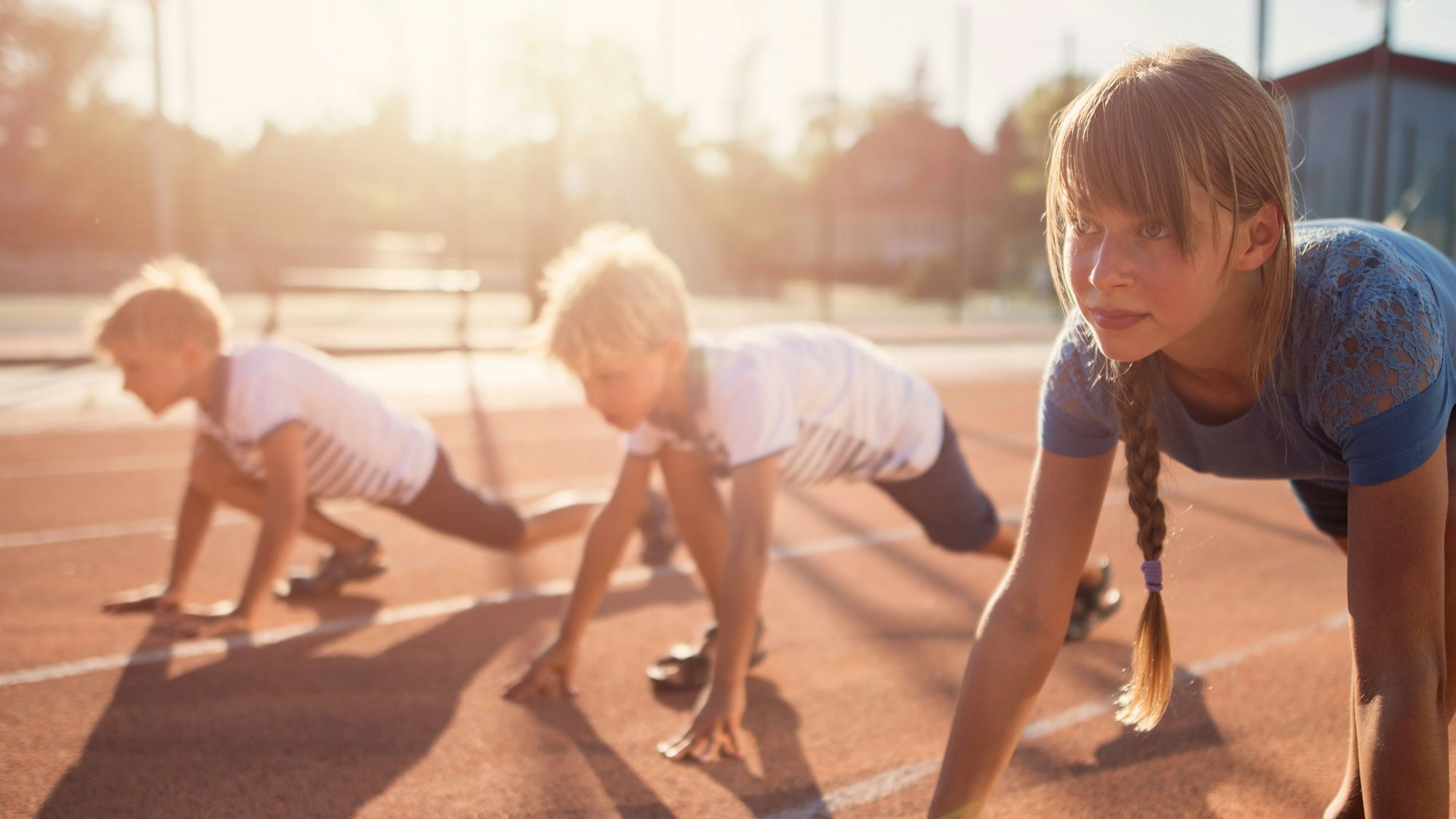 Drei Kinder kurz vor dem Startschuss eines Wettrennens.