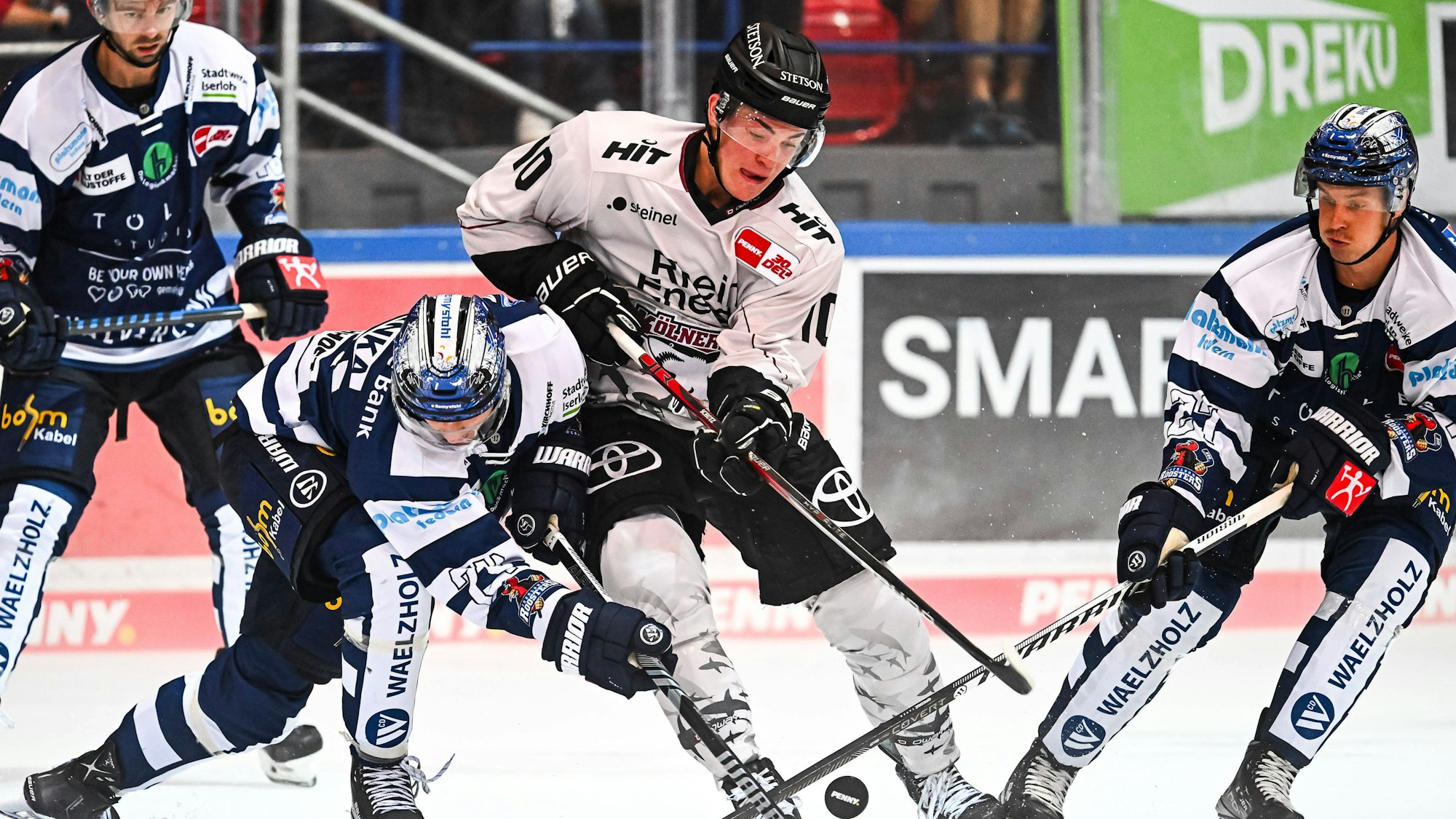 Vier Eishockeyspieler stehen auf dem Eis und kämpfen um den Puck.