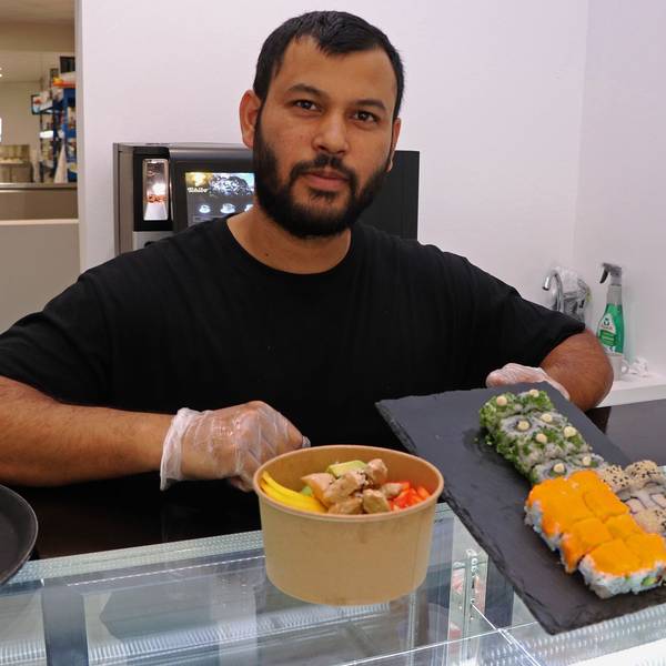Das Bild zeigt einen Mann, der in seinem Restaurant Sushi und Bowls anbietet.