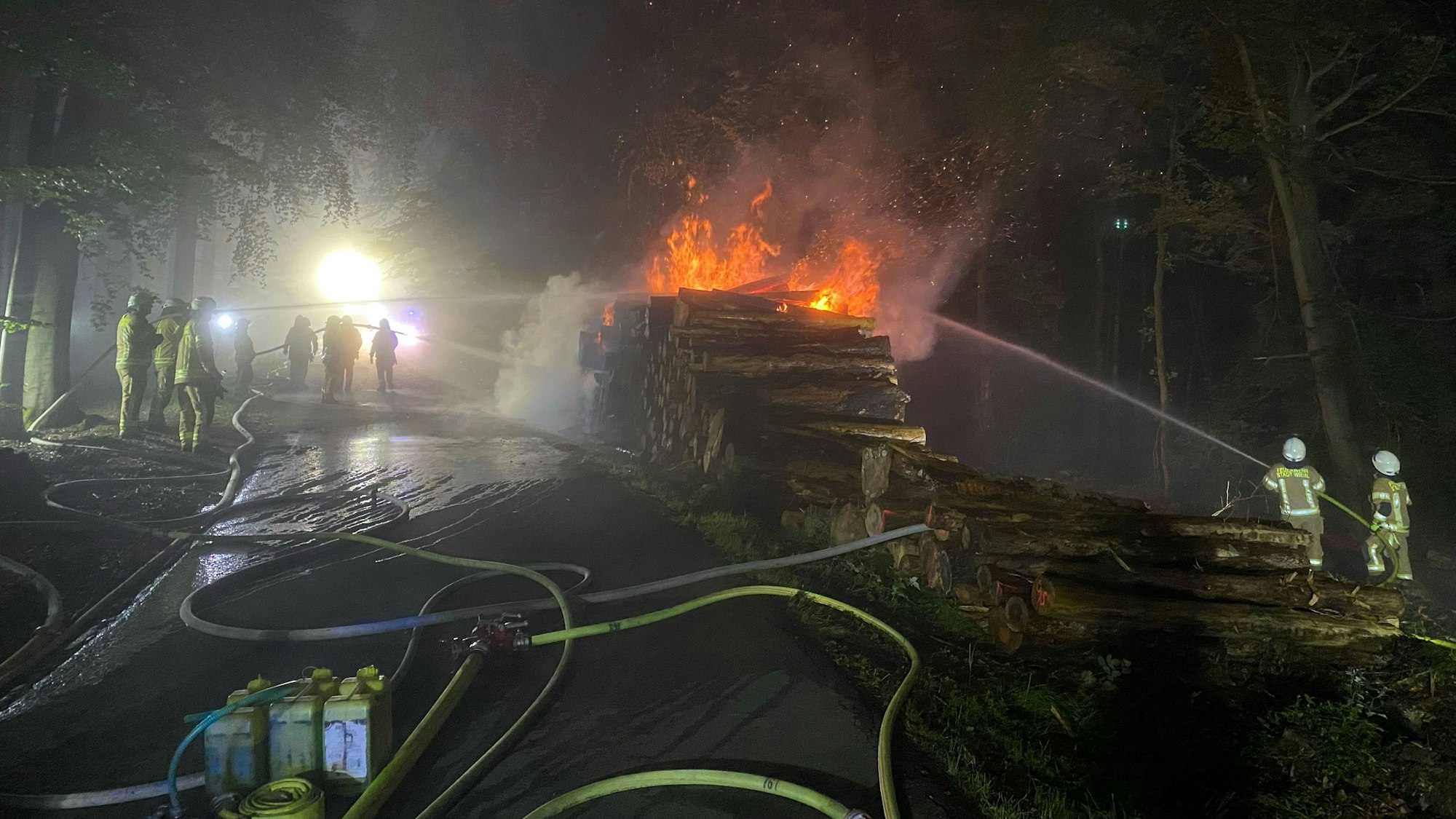 Feuerwehr im Einsatz wegen eines brennenden Holzstapels.