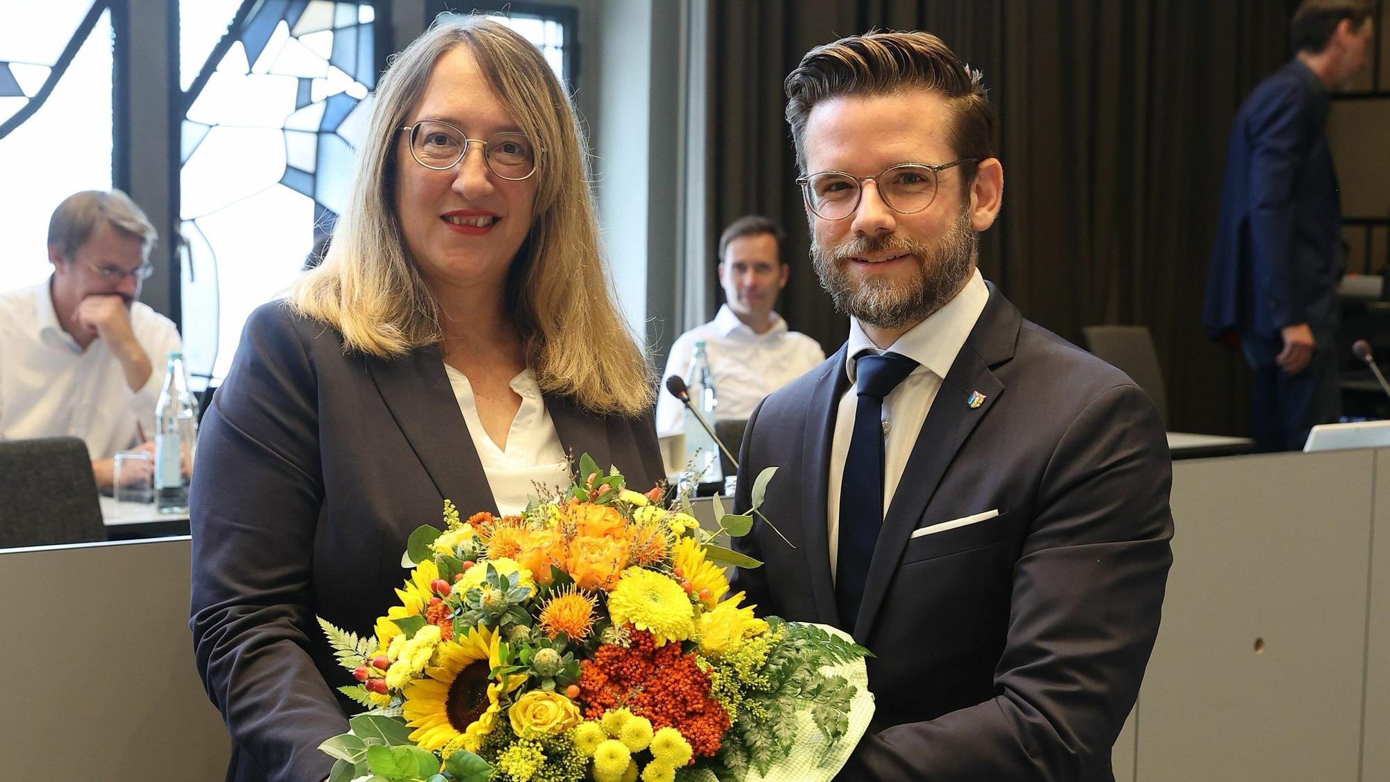 Eine Frau und ein Mann posieren mit Blumenstrauß für ein Foto.