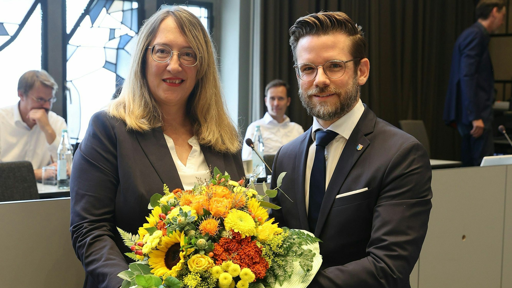 Eine Frau und ein Mann posieren mit Blumenstrauß für ein Foto.