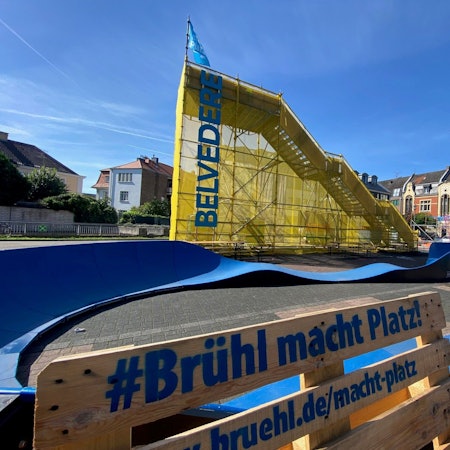 Das Foto zeigt den Belvedere und eine Sitzbank mit dem Schriftzug „Brühl macht Platz“.