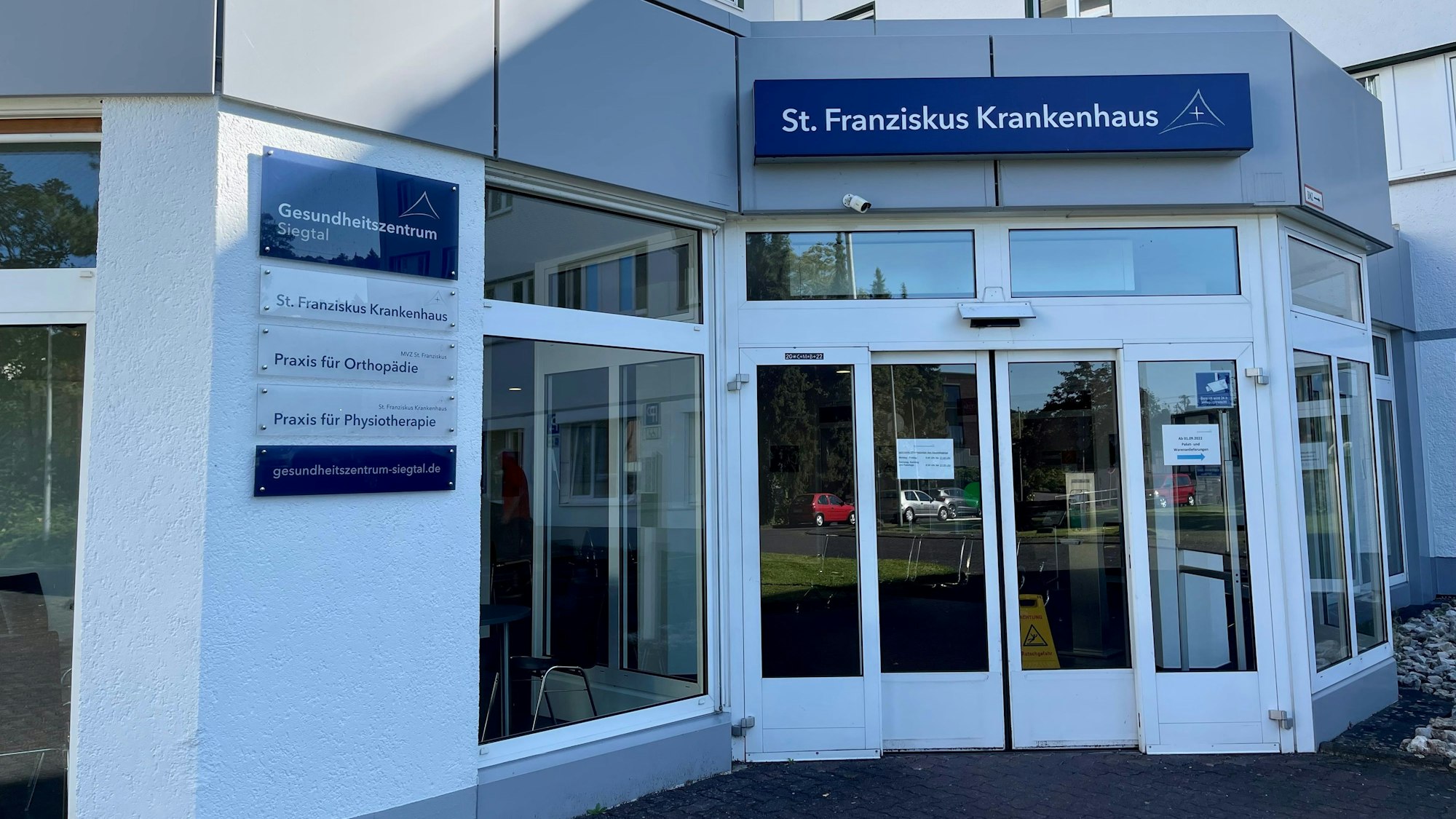 Der gläserne Haupteingang des St. Franziskus Krankenhauses mit Beschilderung.