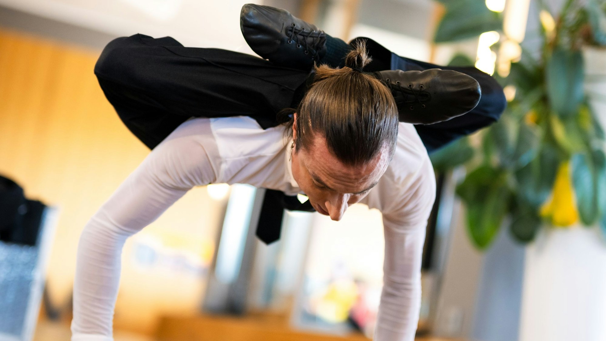 Alexander Batuev balanciert auf seinen Armen und faltet seine Beine hinter dem Kopf.