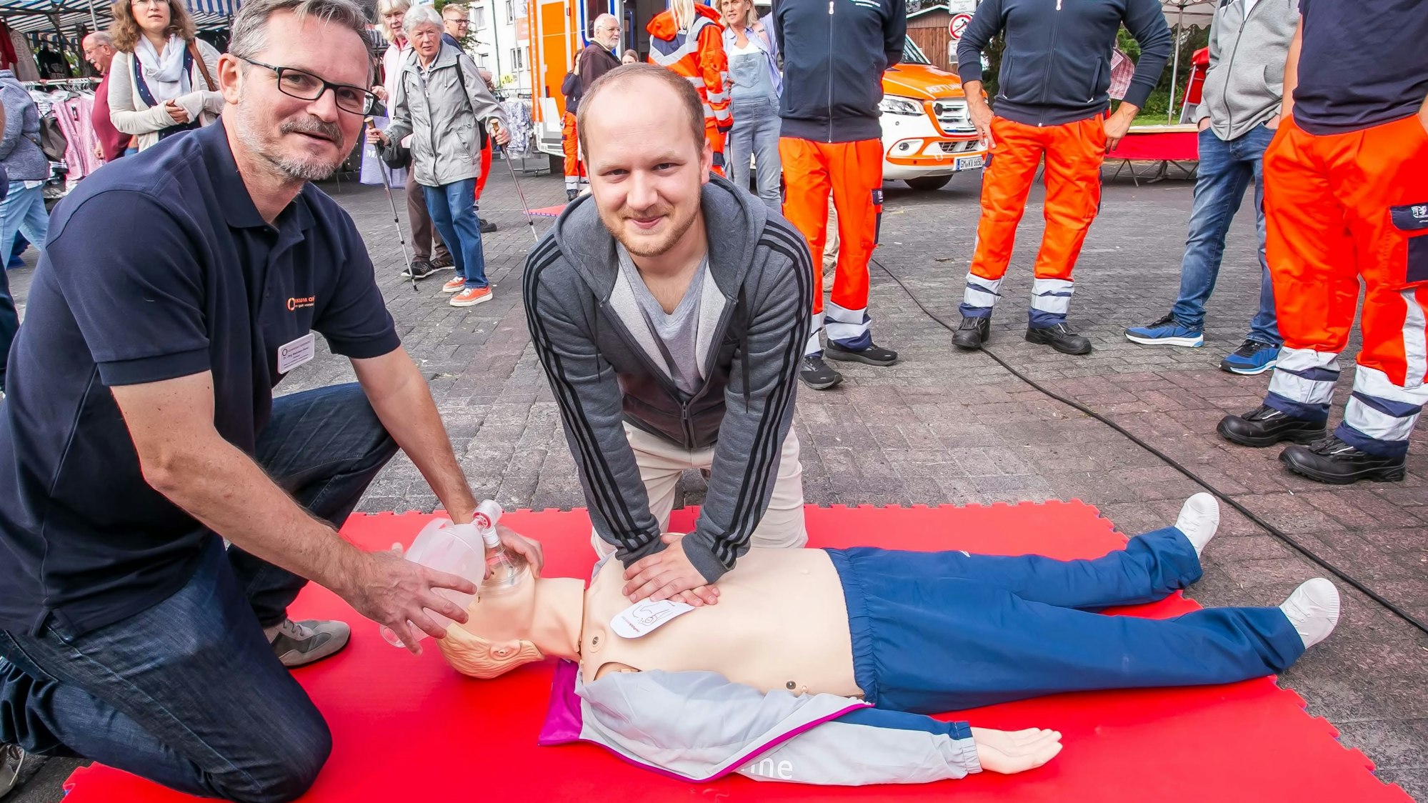 So wird es gemacht: Der Notfallmediziner Dr. Jörg Niehüser-Saran (links) vom Kreiskrankenhaus in Waldbröl erklärt an einer Puppe auf dem Vieh- und Krammarkt in Waldbröl die wertvollen Handgriffe der Wiederbelebung nach einem Herz-Kreislauf-Zusammenbruch. Viele Interessierte nahmen dieses Angebot wahr.