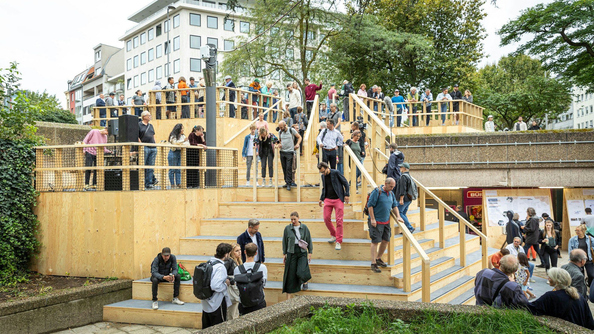 Personen laufen die Freitreppe aus Holz hoch und runter.