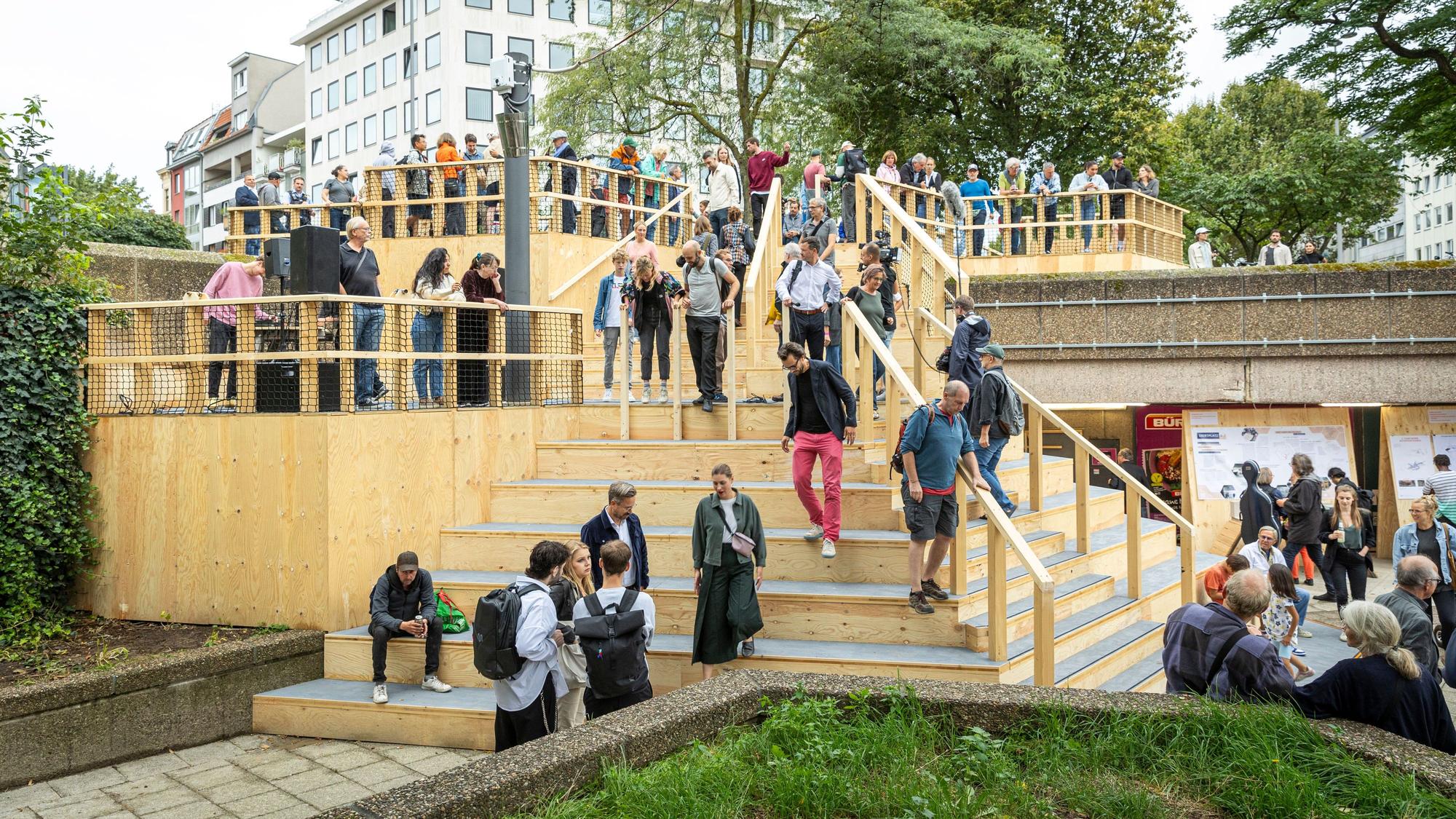 Menschen stehen auf der neuen Holztreppe am Ebertplatz.