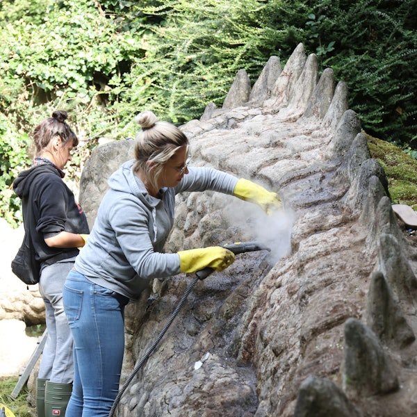 Eine Frau arbeitet an einem Drachen aus Beton.