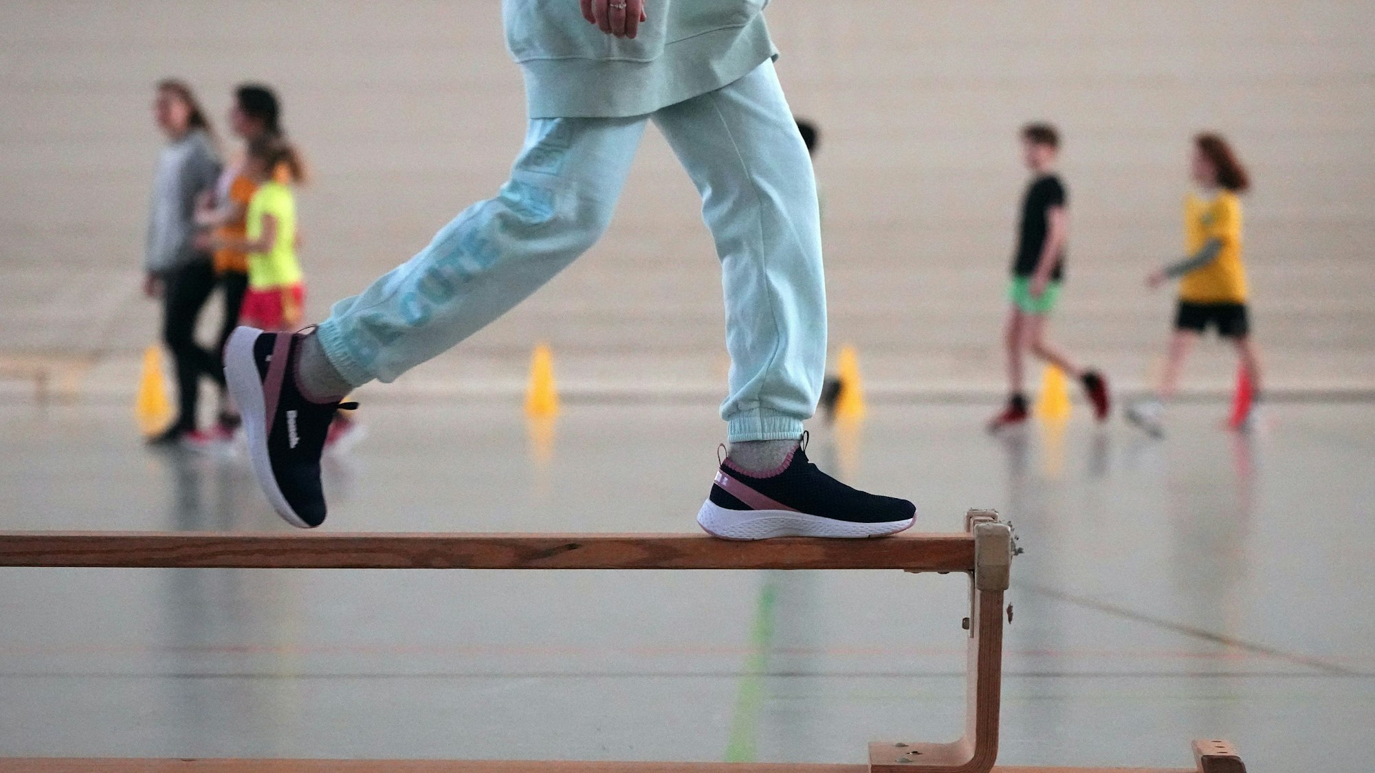 Eine Schülerin der 5. Klasse der Berliner Hunsrück-Grundschule läuft im Sportunterricht über eine umgedrehte Holzbank.