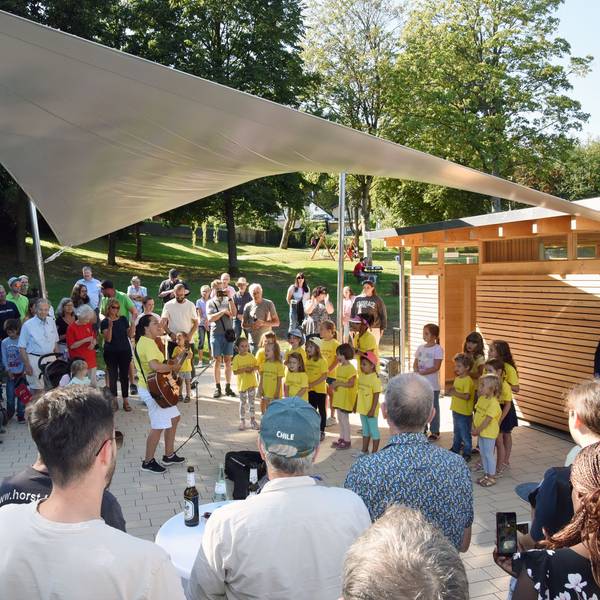 Ein Kinderchor wird von Festbesuchern umringt.