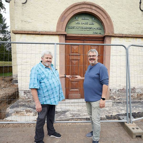 Zwei Männer stehen vor dem mit einem Bauzaun abgesperrten Portal der Kirche in Schleiden.