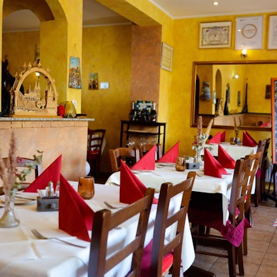 Blick in den gelb gestrichenen Gastraum mit gedeckten Tischen im Da Mario.