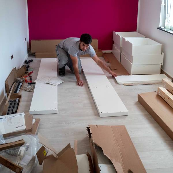 Das Bild zeigt einen Handwerker, wie er einen Schrank zusammenbaut.