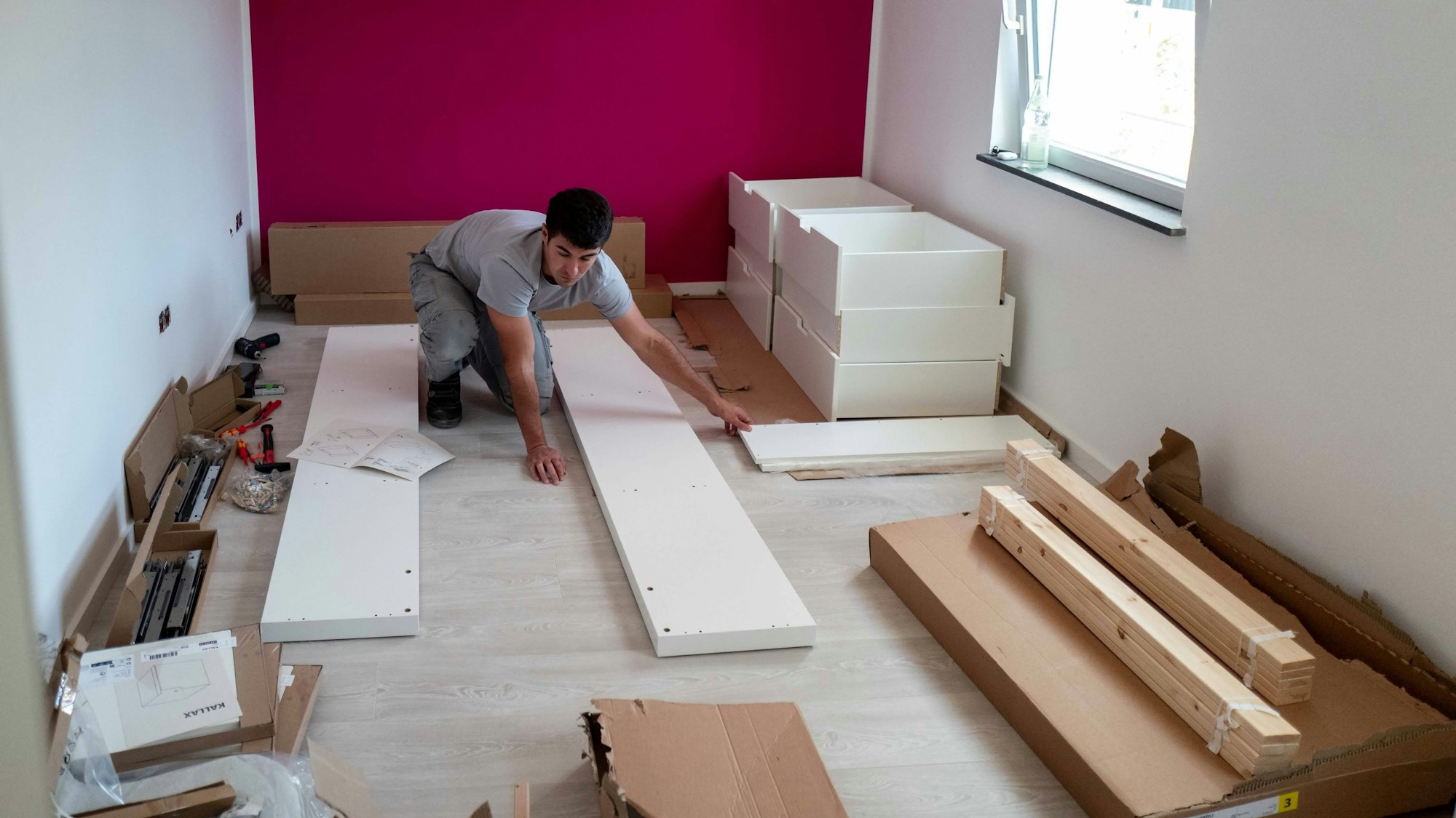 Das Bild zeigt einen Handwerker, wie er einen Schrank zusammenbaut.