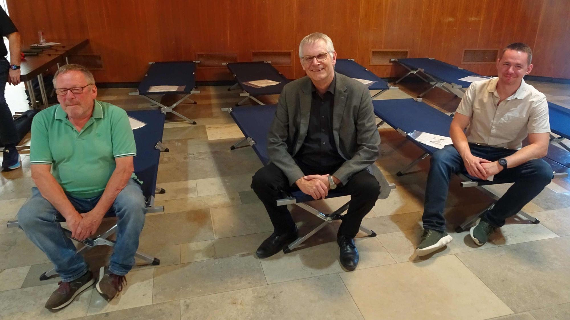 Auf Feldbetten: Bürgermeister Ludger Banken (Mitte), Peter Heck (UWG, links) aus Oberdrees und Pascal Gressmann, Sachbearbeiter Bevölkerungs- und Katastrophenschutz der Stadt Rheinbach.