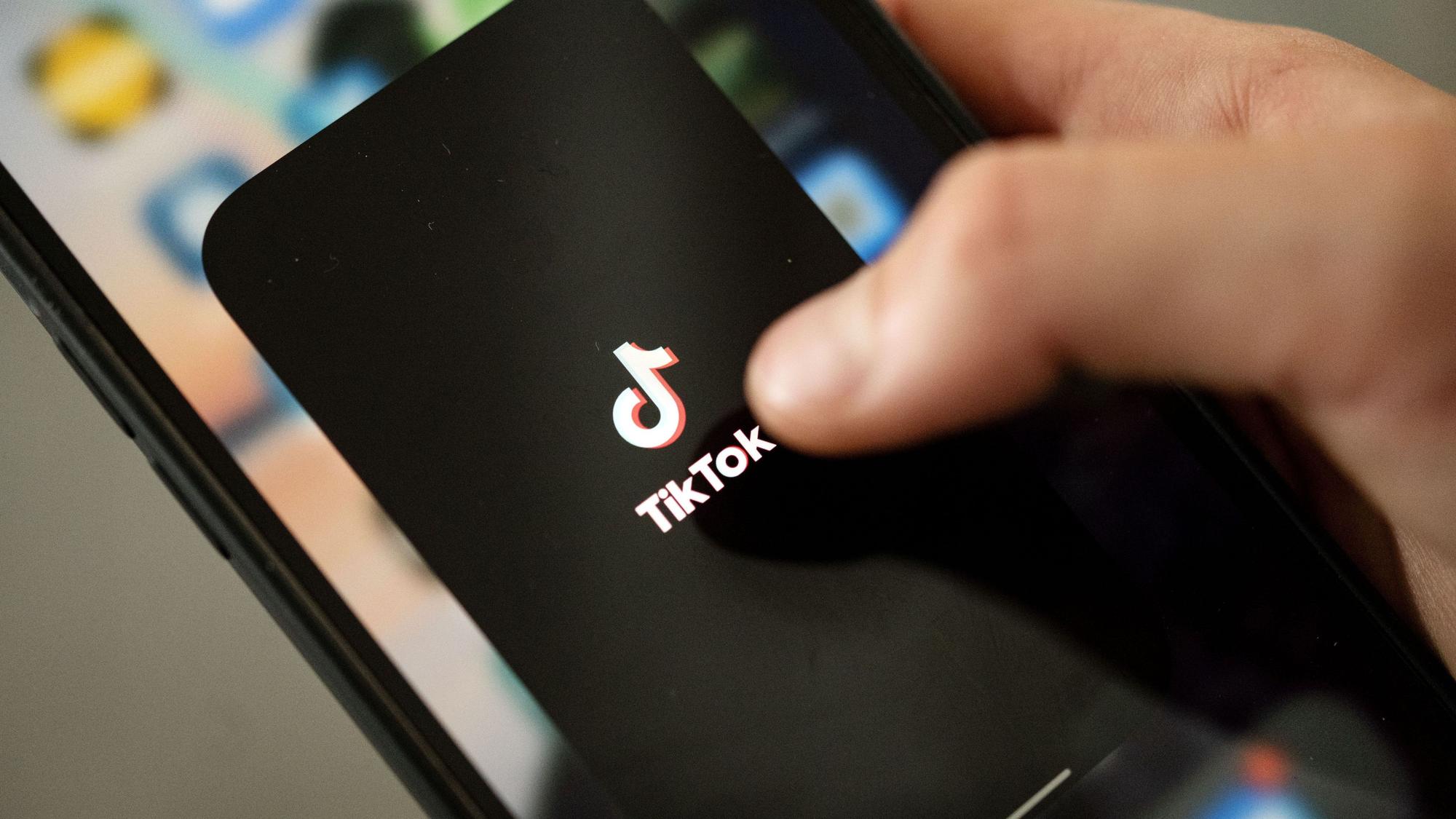 Ein Teenager tippt auf das TikTok-Logo auf einem Smartphone.