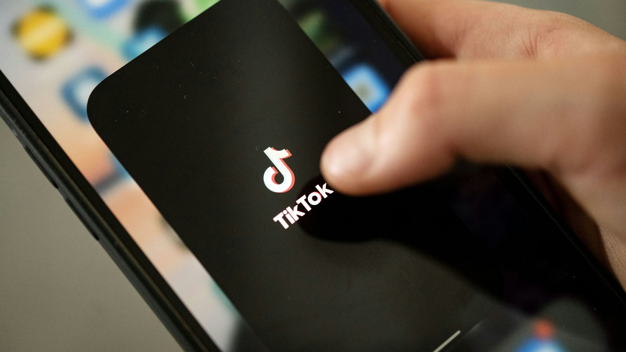 Ein Teenager tippt auf das TikTok-Logo auf einem Smartphone.