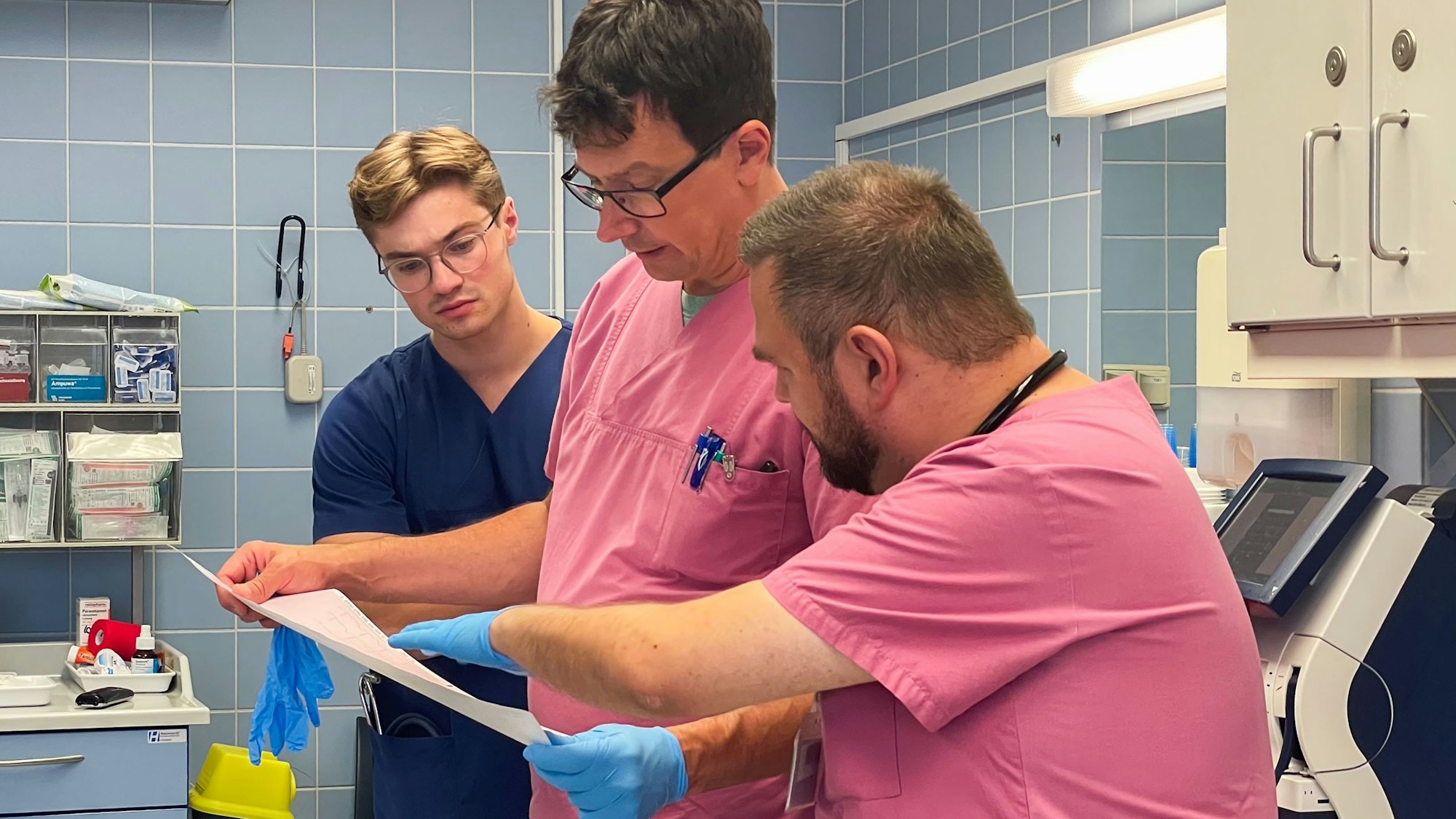 Drei medizinische Mitarbeiter in der Notaufnahme des Euskirchener Marienhospitals schauen auf ein Blatt Papier.
