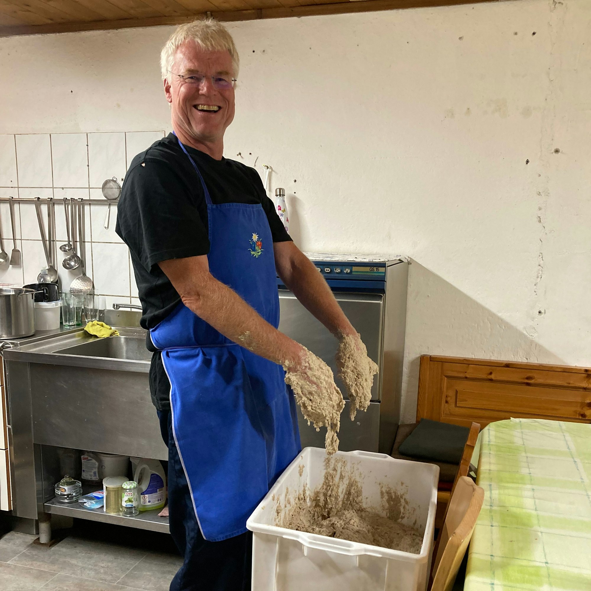 Frank Eggeling knetet mit den Händen in einem großen Behälter mit Kloßteig.