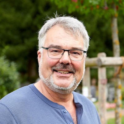 Pfarrer Erik Schumacher lächelt in die Kamera. Er trägt Brille und einen gepflegten Bart.