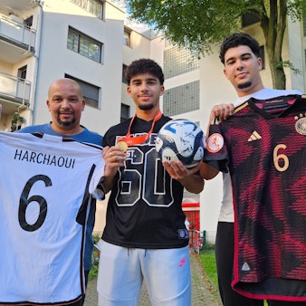 Auf dem Foto halten Fayssal, sein Vater Mohammed und Bruder Imad Trikots in die Kamera.