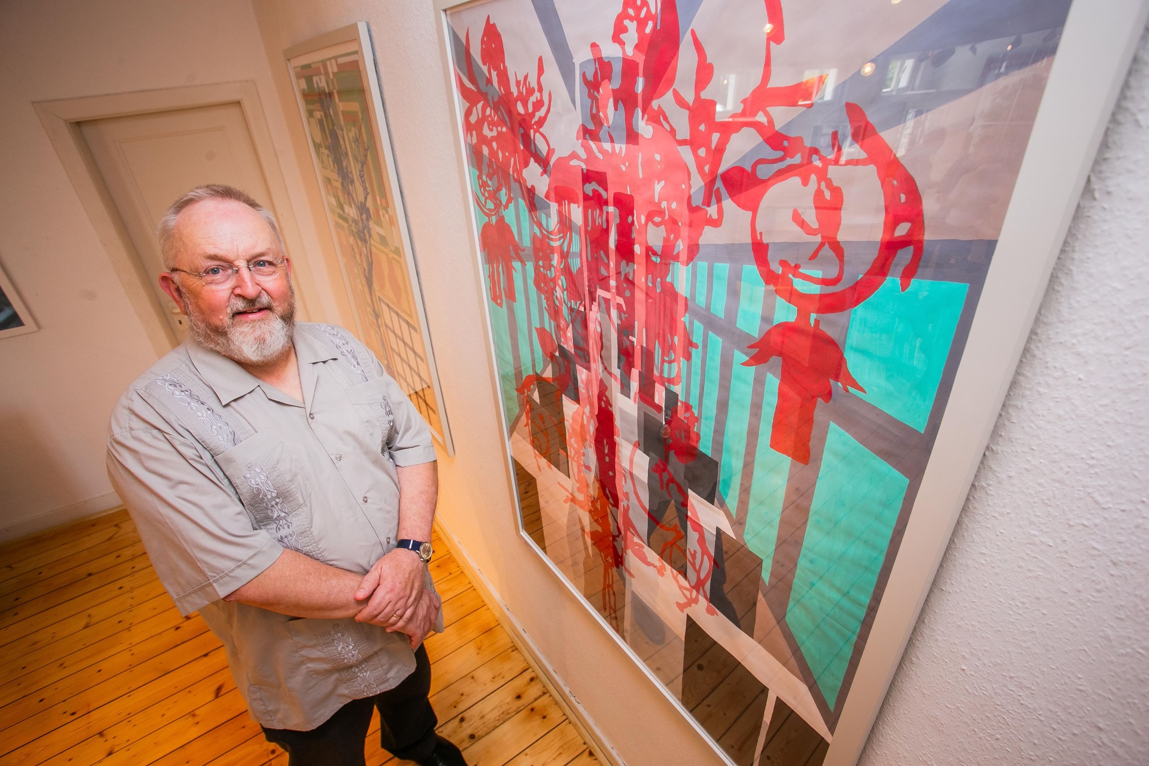 Im Bild ist ein Künstler vor einem seiner Bilder.
