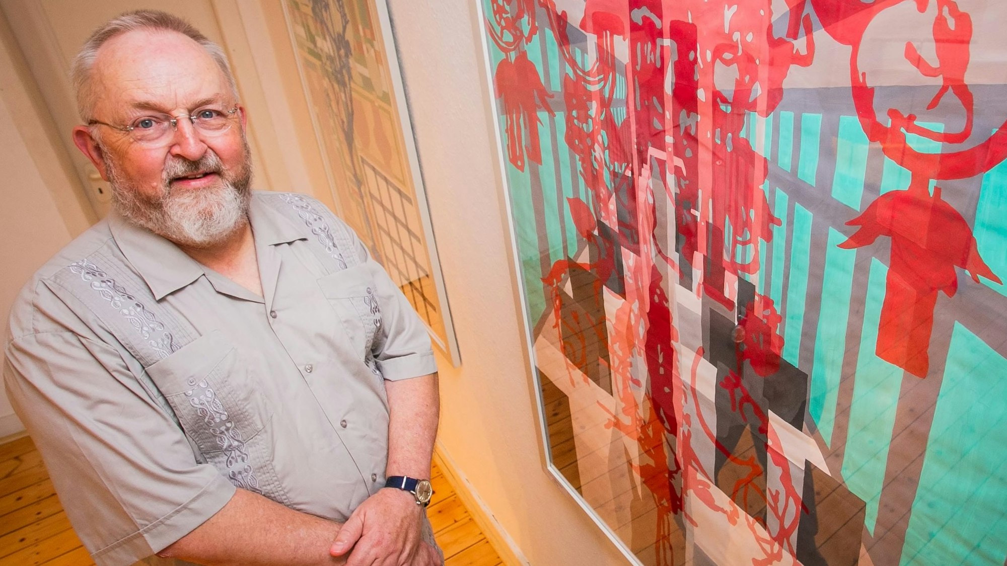 Im Bild ist ein Künstler vor einem seiner Bilder.