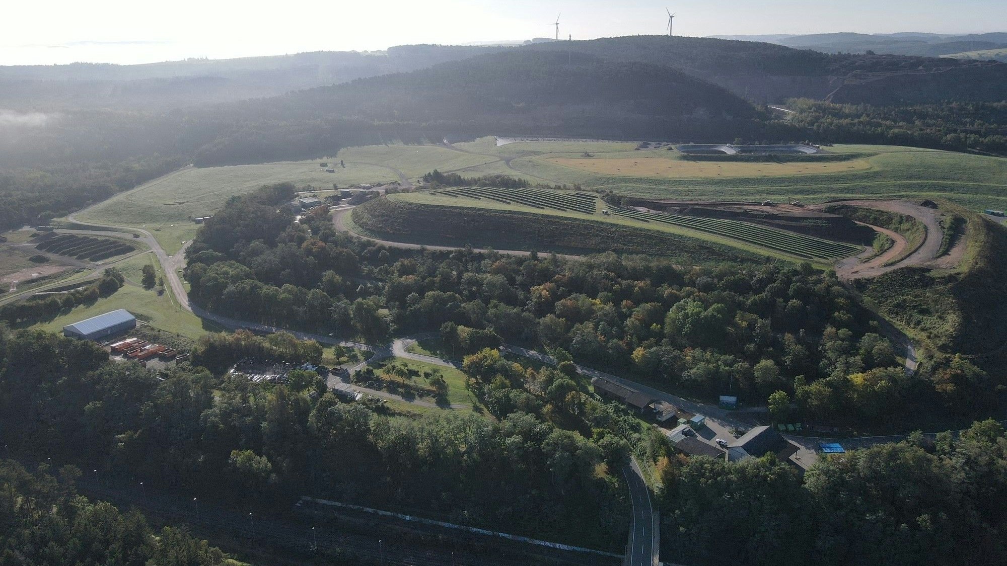 Eine Luftaufnahme zeigt ein Abfallwirtschaftszentrum, umgeben von Bäumen.