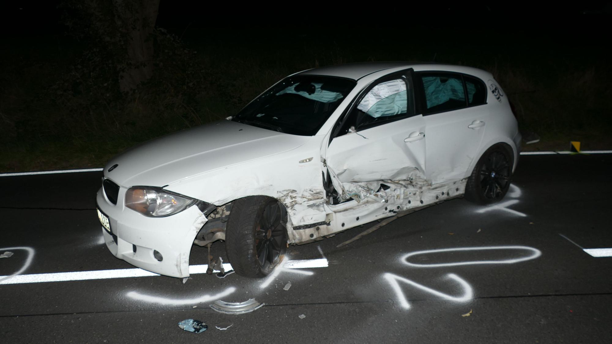 Ein zerbeultes Auto steht nachts auf de Straße.