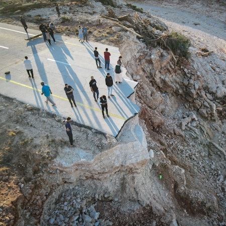 Menschen stehen an einer durch die Überschwemmungen zerstörten Straße im Osten Libyens nahe der Hafenstadt Darna, wo 20.000 Tote befürchtet werden.