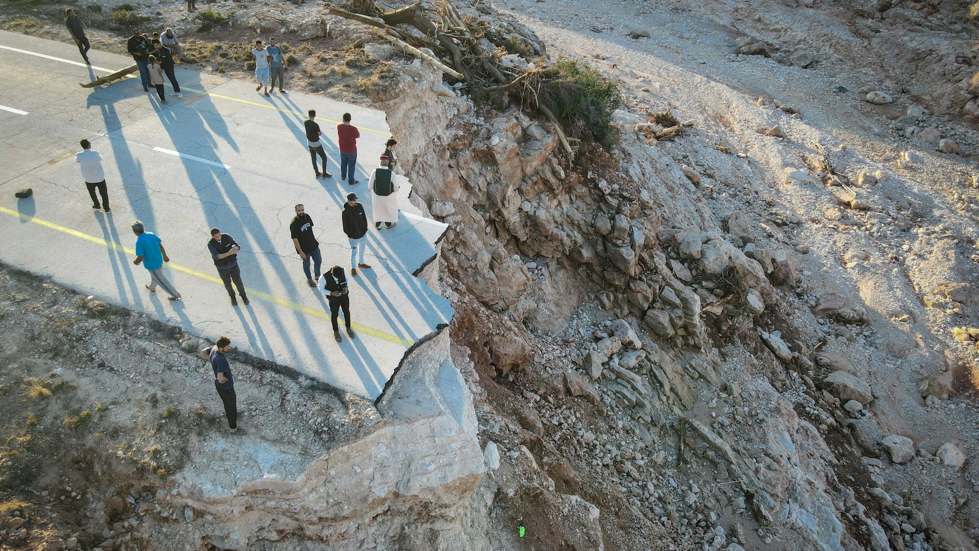 Menschen stehen an einer durch die Überschwemmungen zerstörten Straße im Osten Libyens nahe der Hafenstadt Darna, wo 20.000 Tote befürchtet werden.