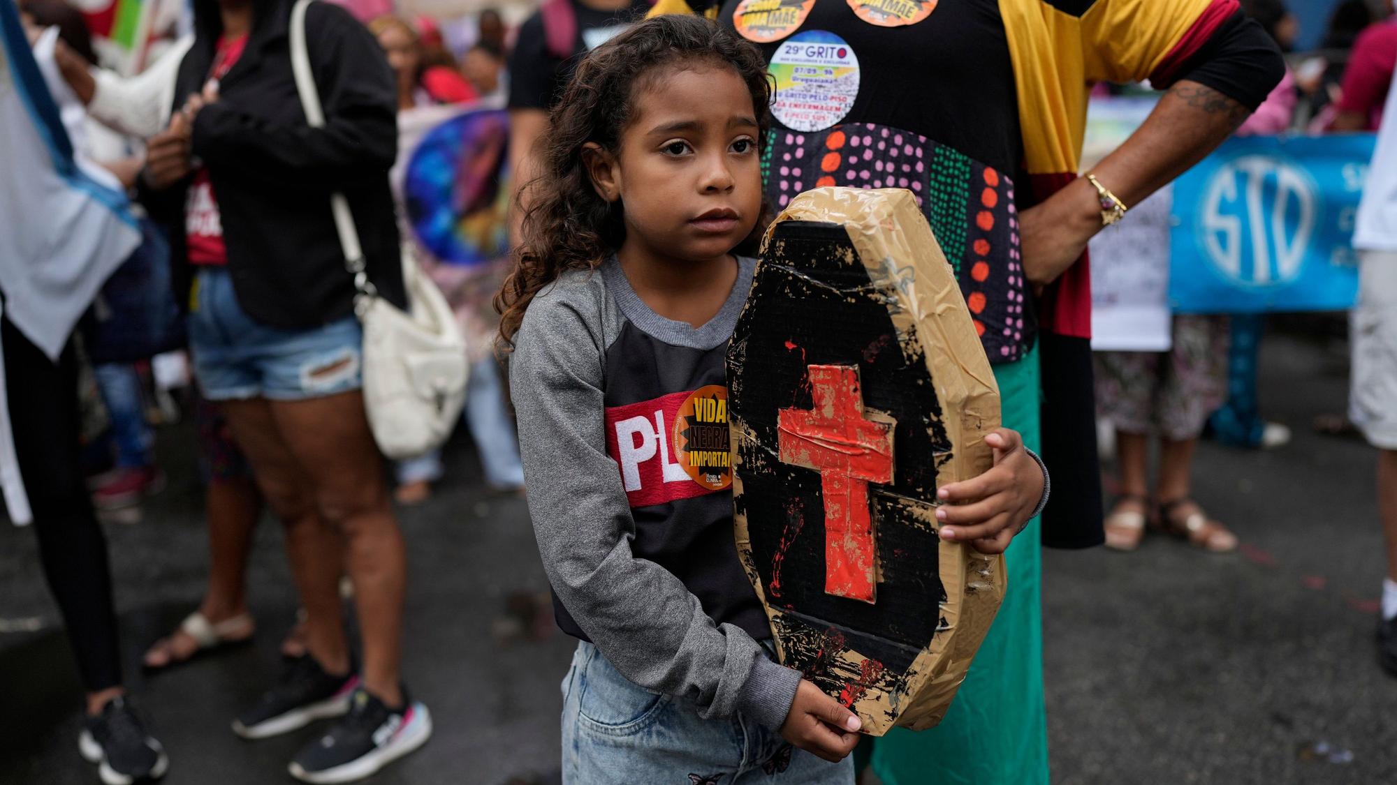 A child holds a small, mock coffin as relatives of people killed in police operations, against suspected drug traffickers and thieves in favelas, attend a march coined "The scream of the excluded" to call for a more democratic nation and to put an end to economic inequality, on Independence Day in Rio de Janeiro, Brazil, Thursday, Sept. 7, 2023. (AP Photo/Silvia Izquierdo)
