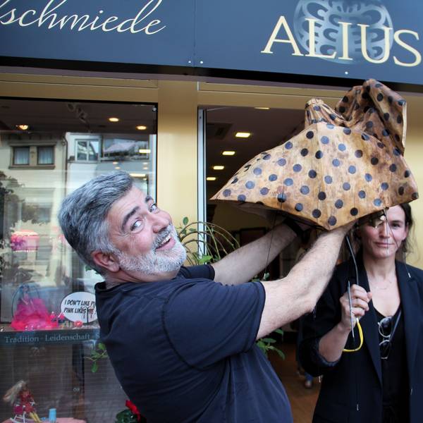 Zwei Menschen spannen einen Schirm aus Holz auf.
