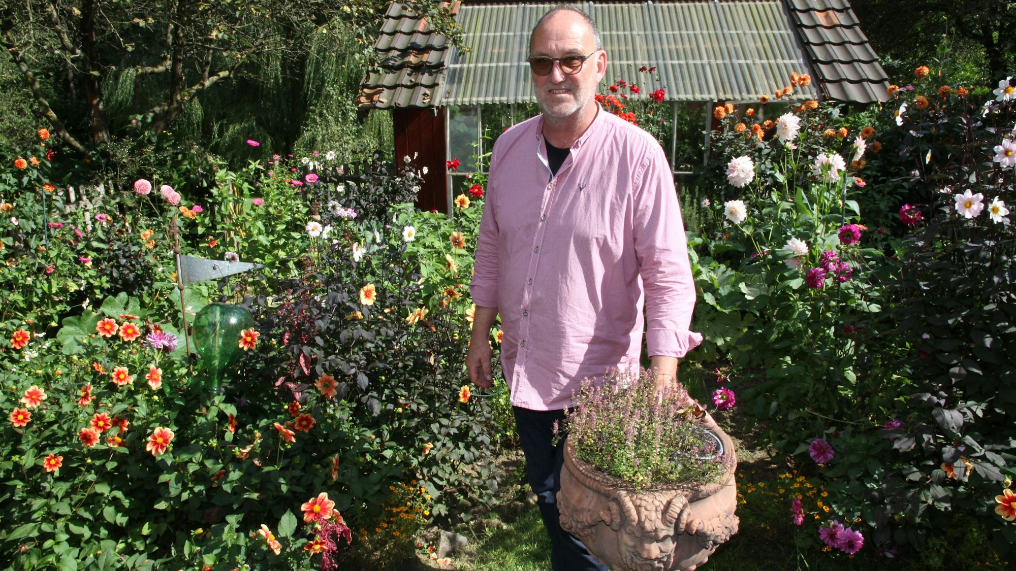 Ein Mann steht inmitten üppig blühender Blumen.