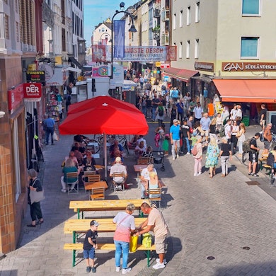 Blick auf die Severinstraße von oben, Menschen sitzen und gehen über die Straße.
