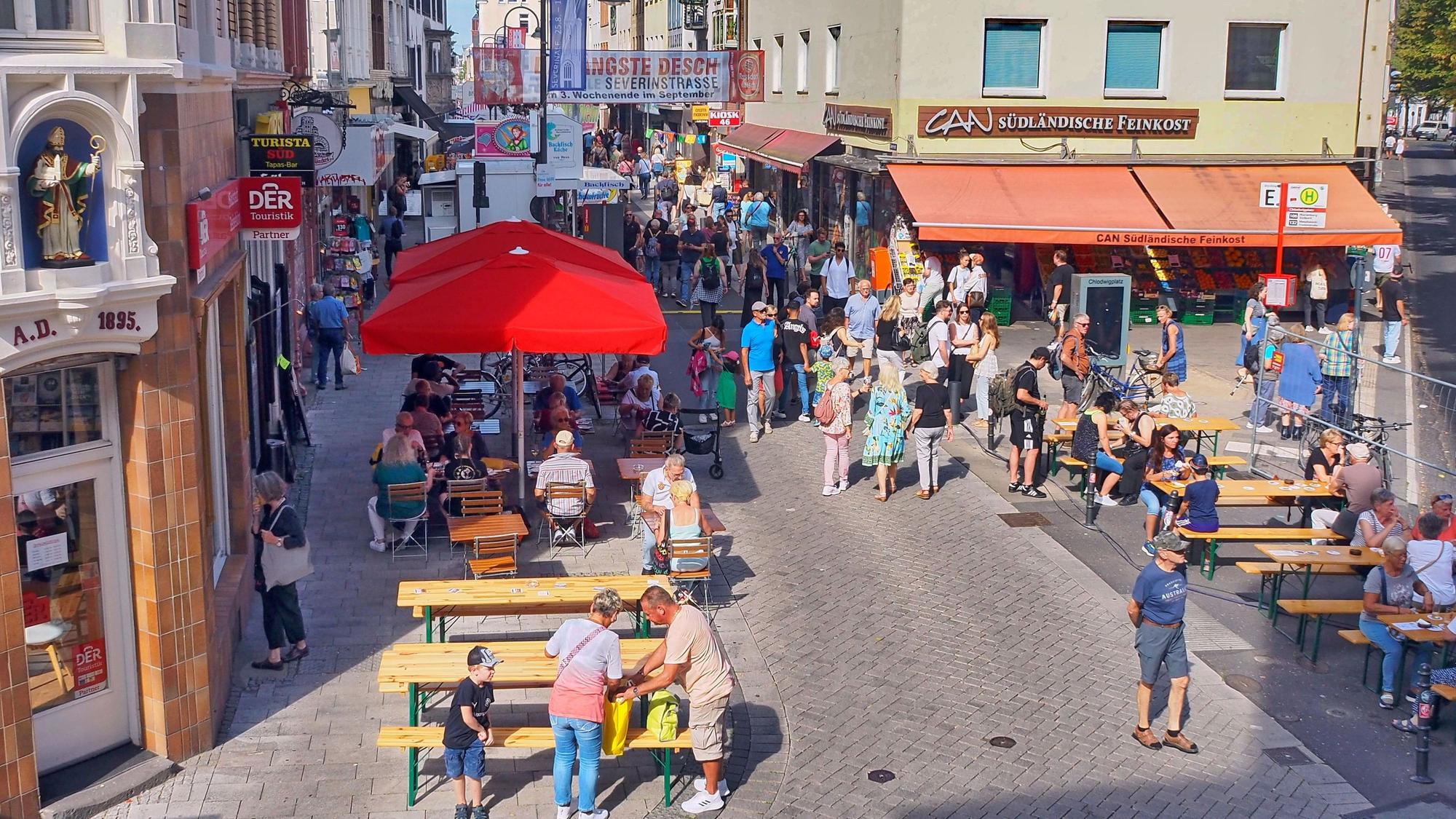 Blick auf die Severinstraße von oben, Menschen sitzen und gehen über die Straße.