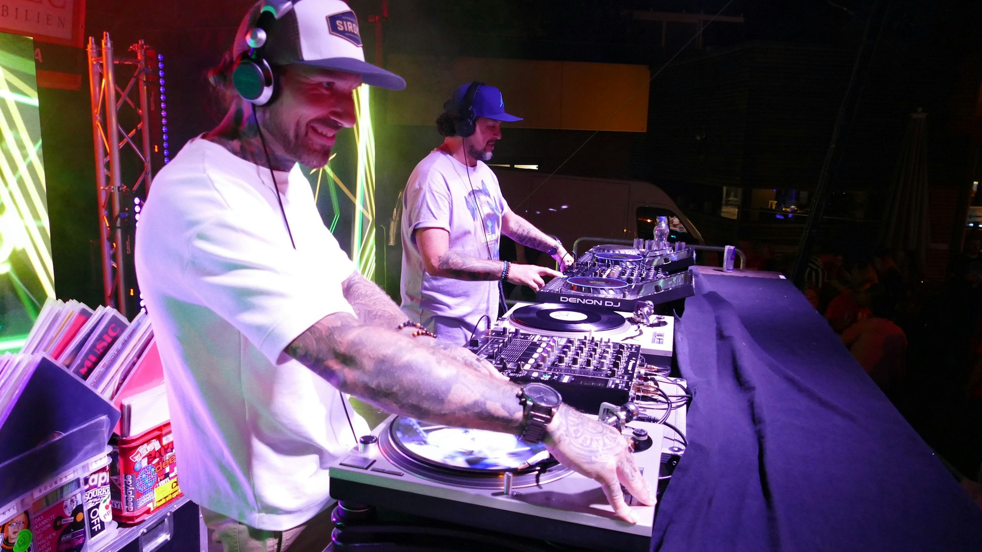 Zwei DJs an ihren Mischpulten legen Platten auf.