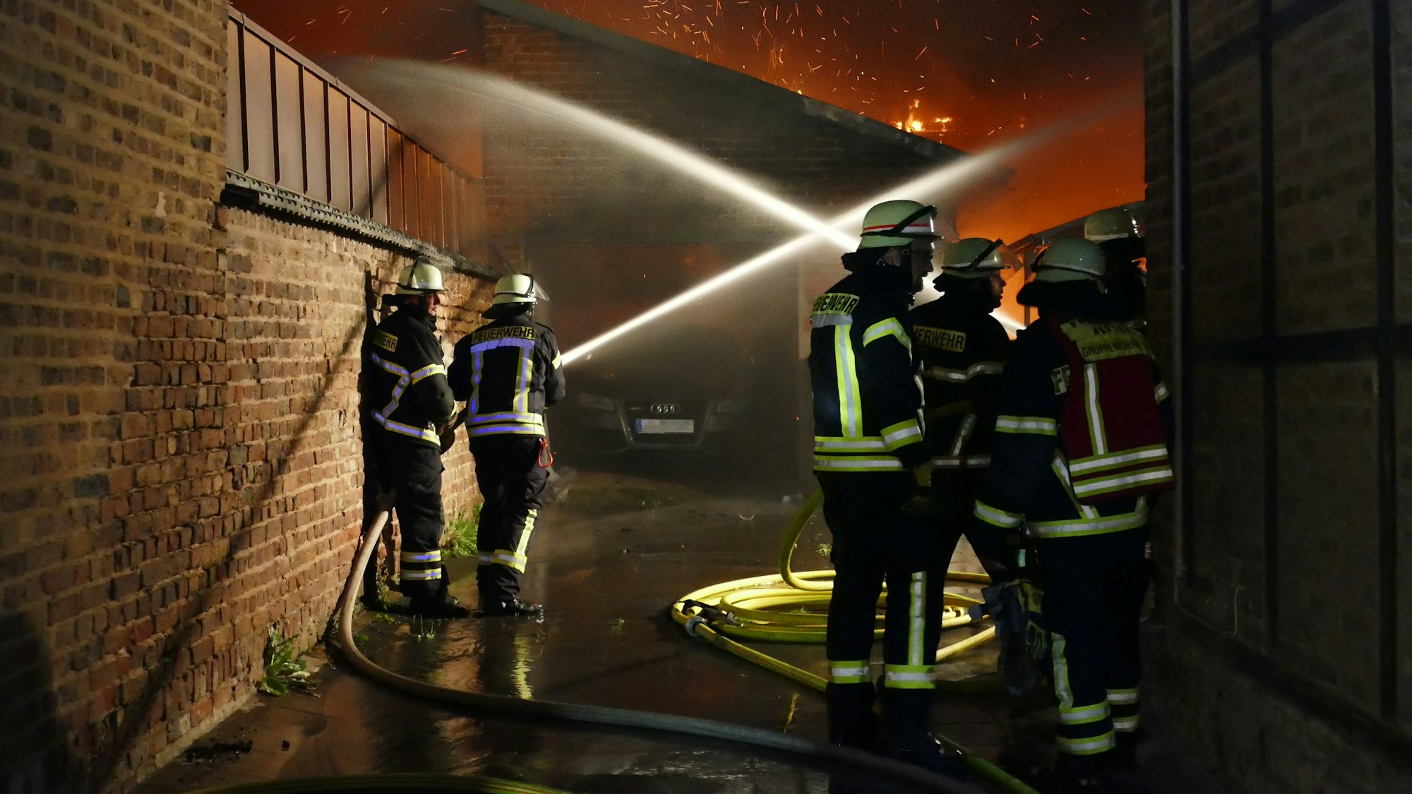 Aus sicherer Entfernung spritzen Feuerwehrleute Wasser auf den Brandherd.