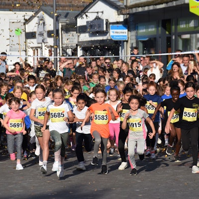 Zahlreiche Kinder starten unter Konfettiregen bei einem Stadtlauf an der Ziellinie.
