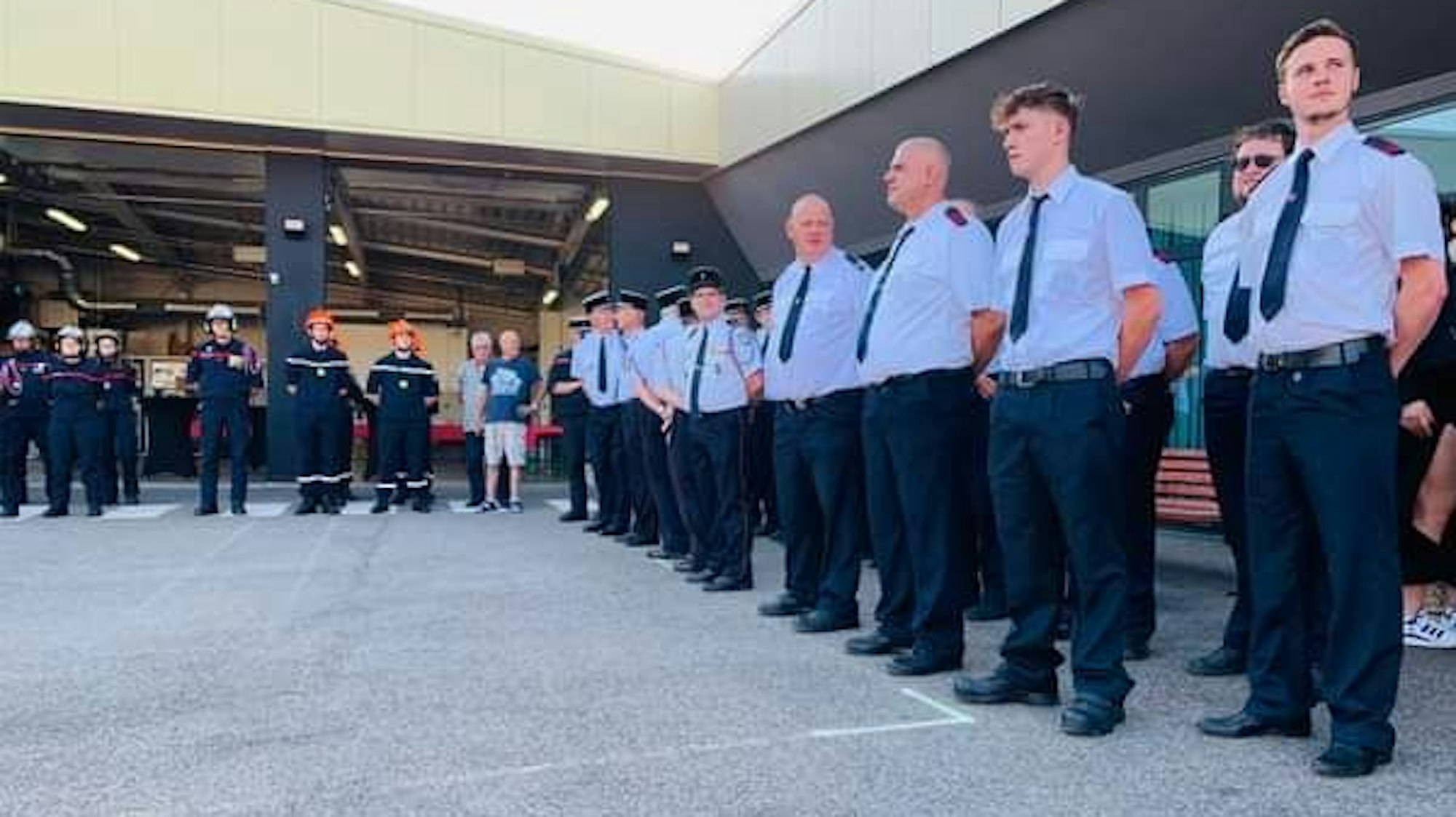 Französische und deutsche Feuerwehrleute stehen um einen Platz.
