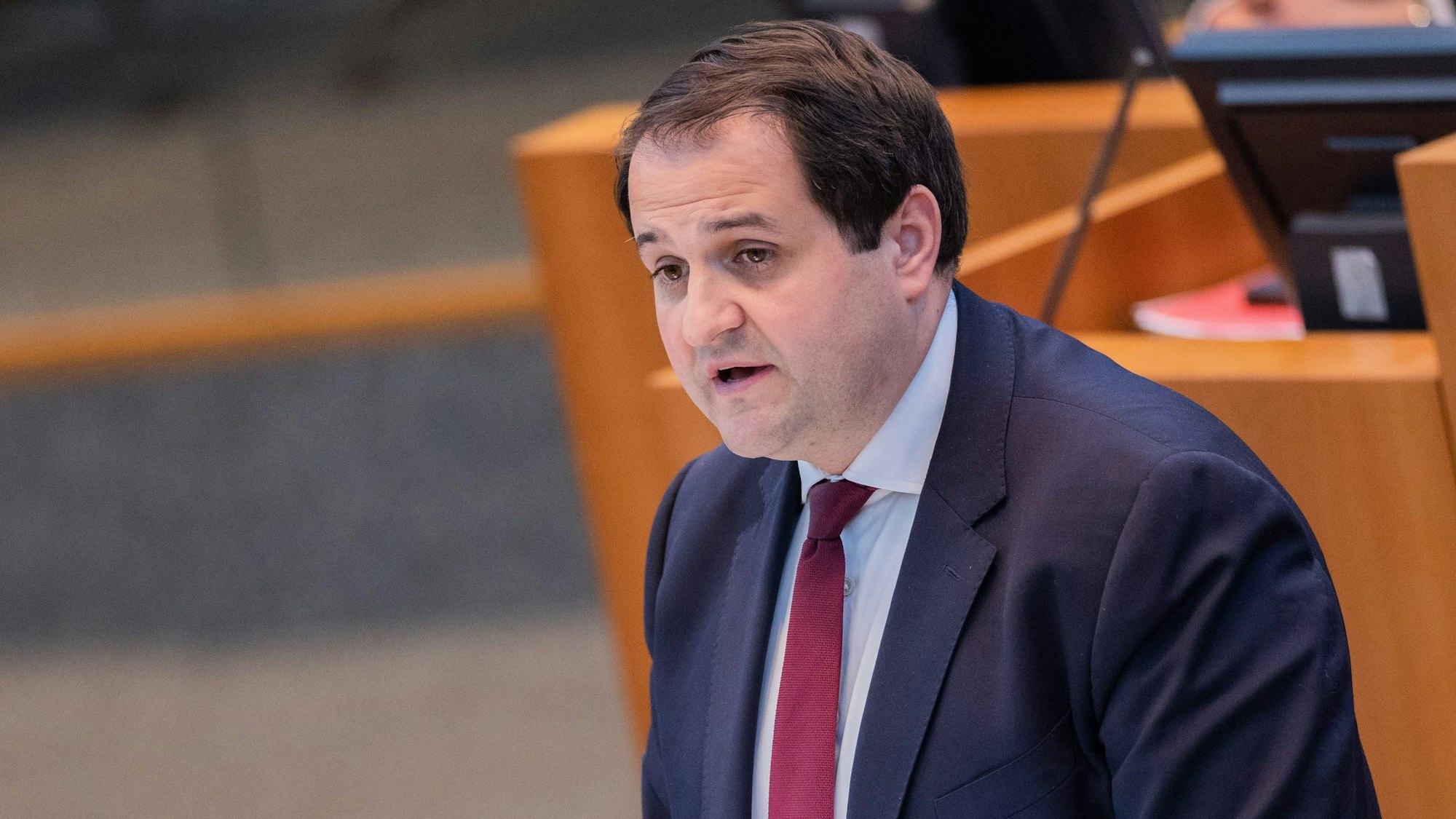 Nathanael Liminski (CDU) spricht vor einem unscharfen Pult mit Rechner im Anzug und Krawatte.