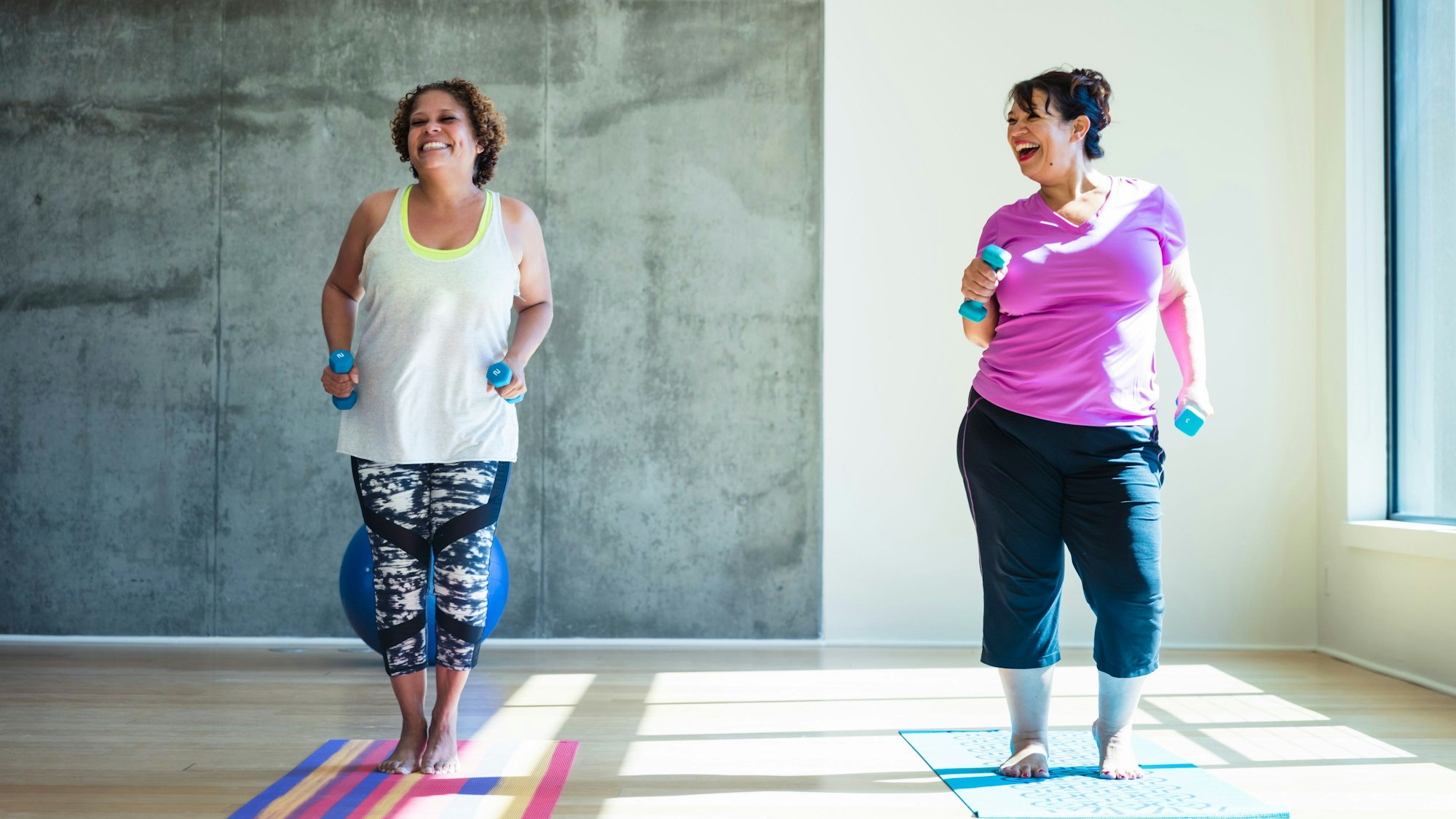 zwei Frauen mit Hanteln auf Sportmatten