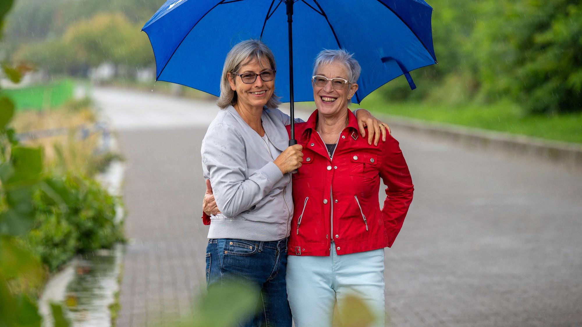 Sibylle Kaminski und Rosa Henkel stehen unter einem blauen Schirm.