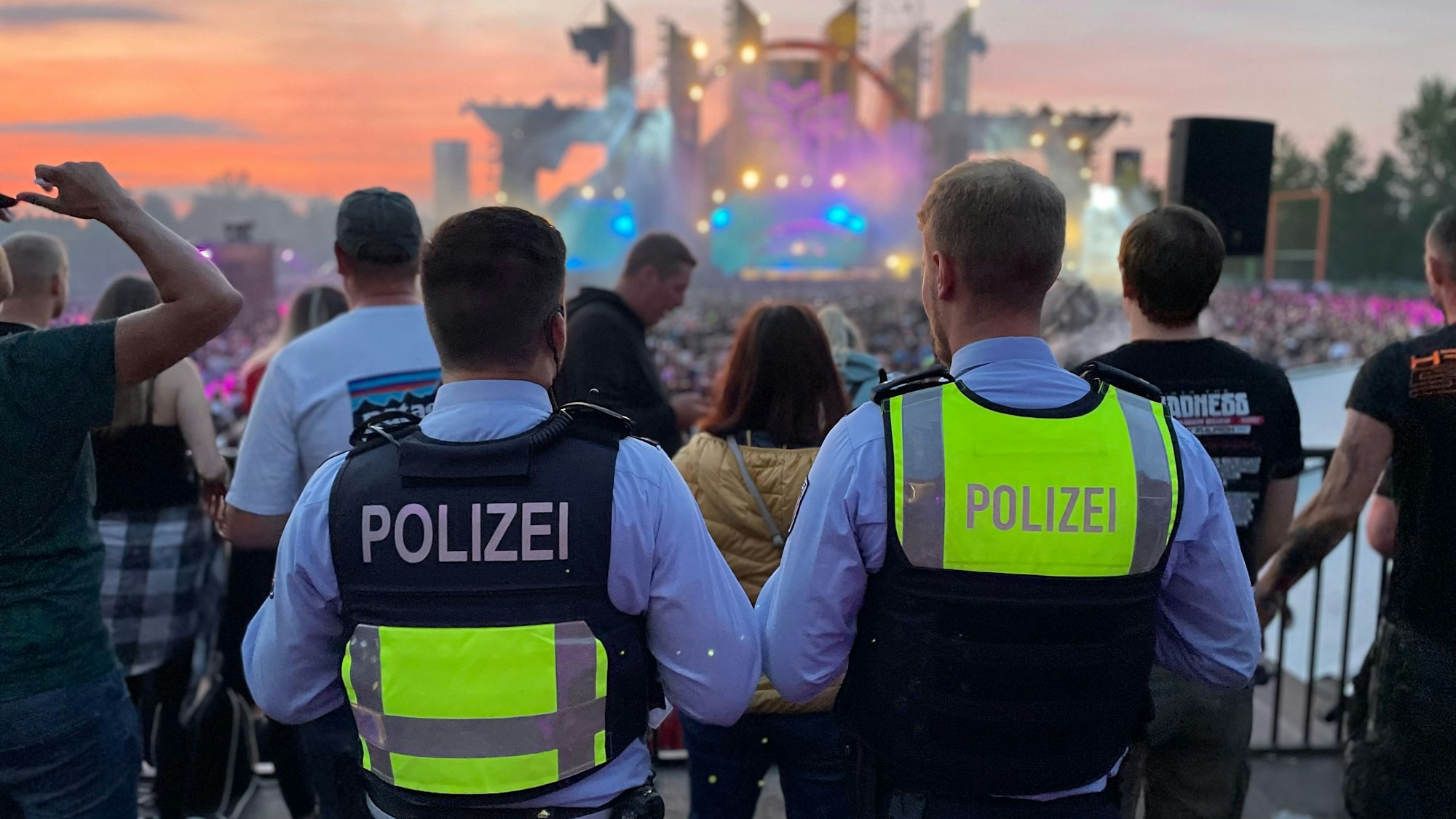 Das Bild zeigt die beiden Polizisten, wie sie auf die Bühne des Festivals schauen.
