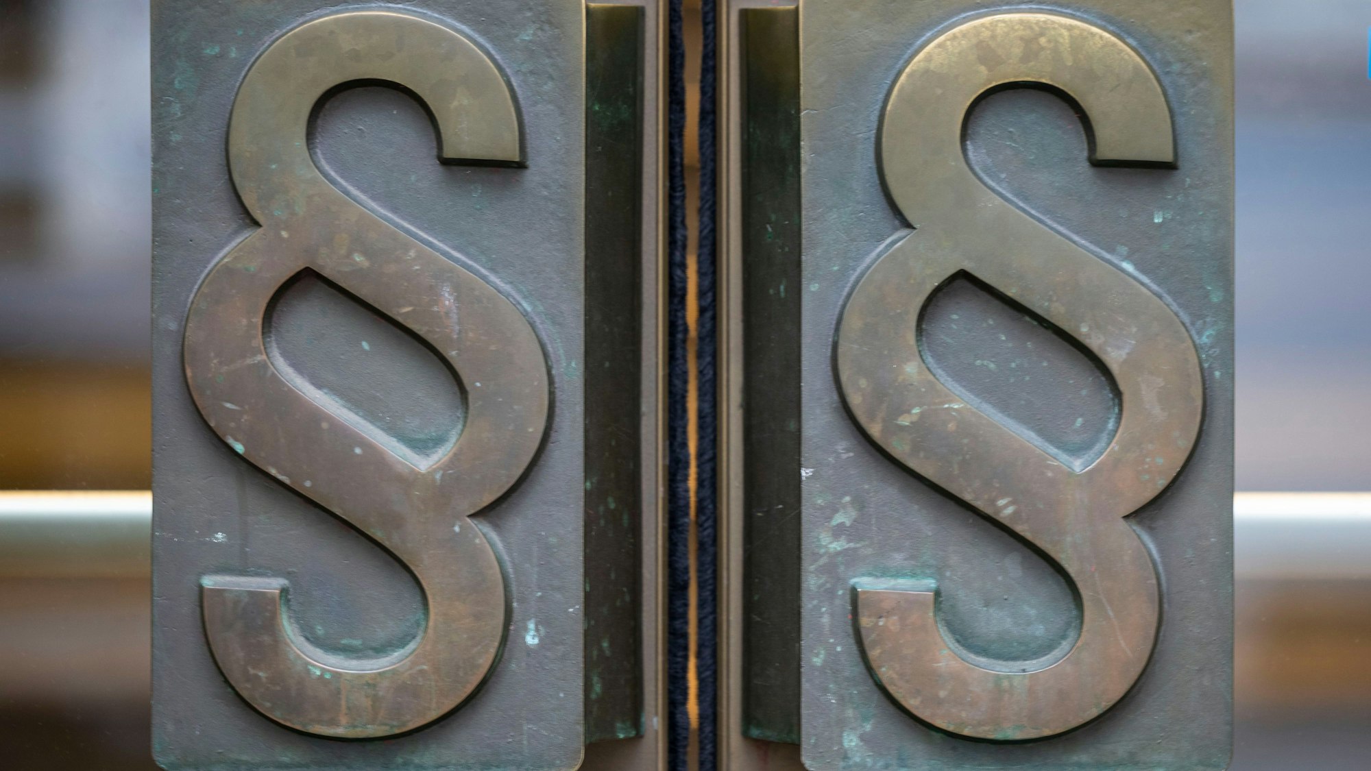 Blick auf das Landgericht in Bonn mit Paragrafen als Türgriff.